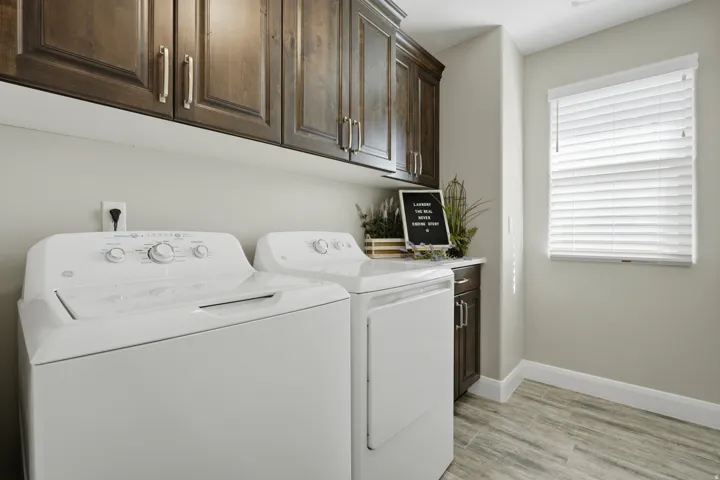 Dark wood-finish cabinetry, light-toned walls, wood-finish flooring, and a window with blinds