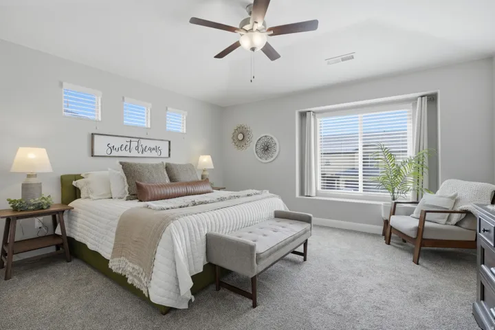 Master bedroom with Recessed window with white blinds, three transom windows, ceiling fan with integrated lighting, and neutral tone carpeting