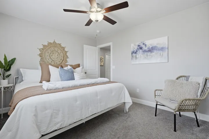 Carpeted flooring, a ceiling fan with integrated lighting, and a paneled interior door