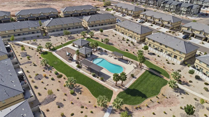 Community swimming pool with surrounding fenced perimeter, shaded lounge areas, and adjacent playground