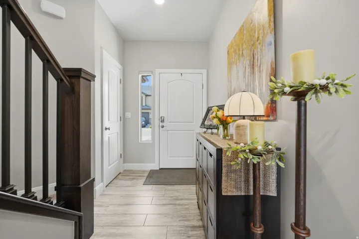 Entryway featuring wood-finish LVP flooring, a dark wood-finish staircase railing with balusters, a white entry door.