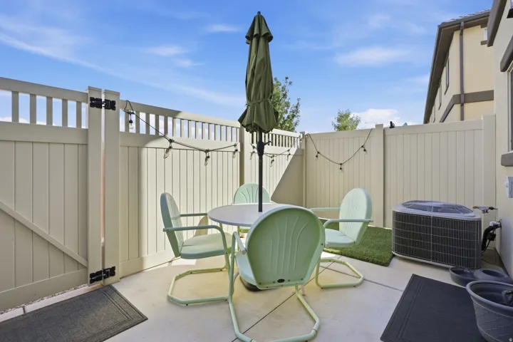 Concrete patio area with a privacy fence and an air conditioning unit
