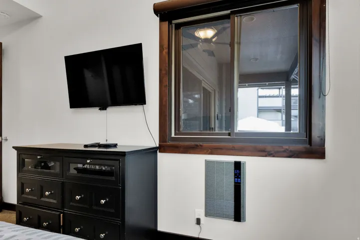Wall-mounted television with a sliding window featuring a wood-finish frame