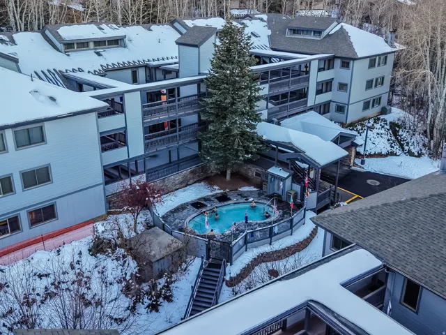 Multi-story property featuring exterior balconies, a fenced outdoor pool, and covered walkways