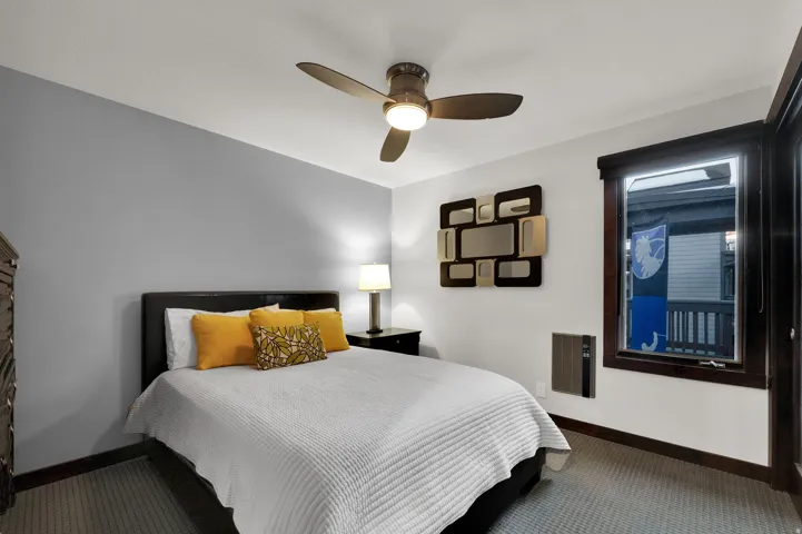 Modern ceiling fan with integrated lighting, a dark wood-finish window frame, and neutral wall paint