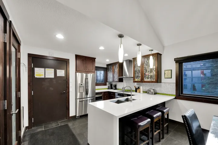 Kitchen featuring a stainless steel refrigerator, dark wood cabinetry, a white countertop island, and recessed lighting