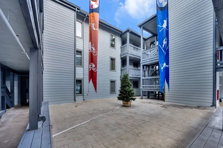 Courtyard with stamped concrete paving, mature potted evergreen, and multi-level exterior balconies