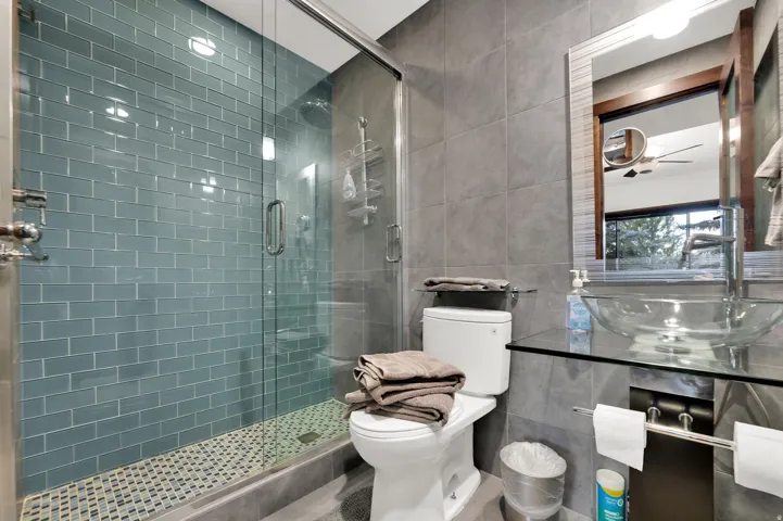 Glass-enclosed shower with blue subway tile and mosaic floor