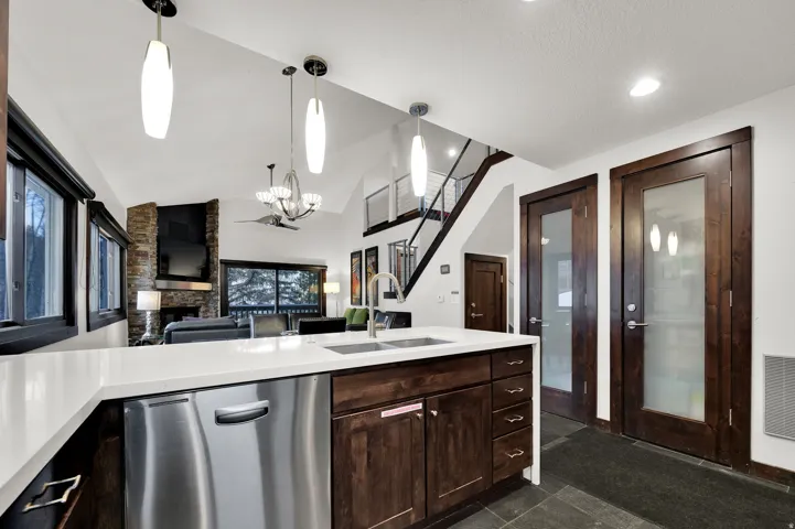 Kitchen island with white countertop, integrated sink, and stainless steel dishwasher