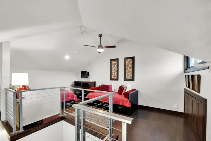 Loft space featuring sloped ceilings, recessed lighting, dark wood-finish flooring, and cable railing