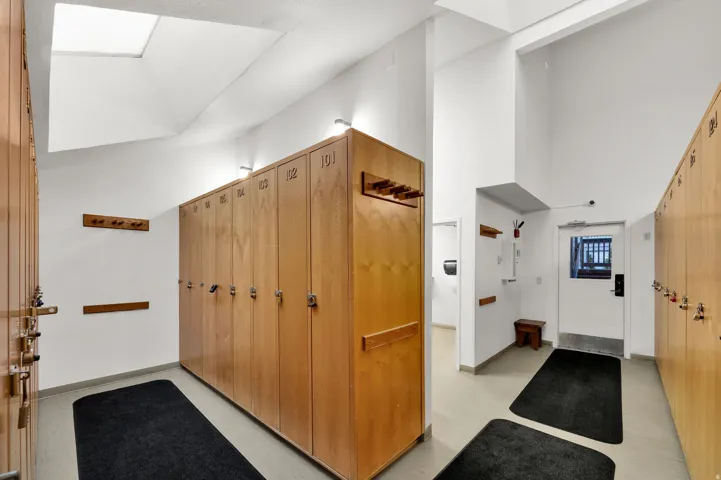 Skylight providing natural light, wood-finish lockers, integrated wall hooks, and light-toned flooring