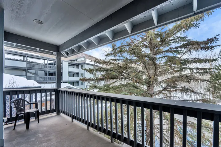 Covered outdoor patio with a durable surface, integrated recessed lighting, and a dark wood-finish railing