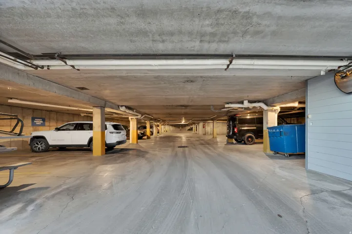 Concrete-floored garage with exposed ceiling pipes and support columns