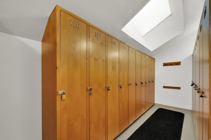 Wood-finish lockers with individual locks and dedicated numbering, complemented by a skylight and wall-mounted coat racks