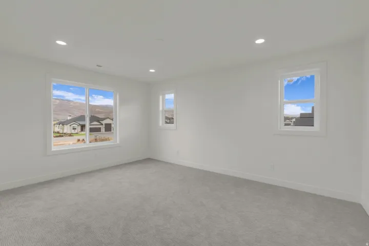 Recessed lighting, light gray carpeting, multiple windows, and white walls