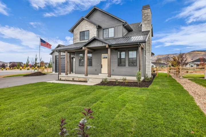 Modern farmhouse exterior with board and batten siding, stone accents, a metal roof, and a covered porch with wood columns