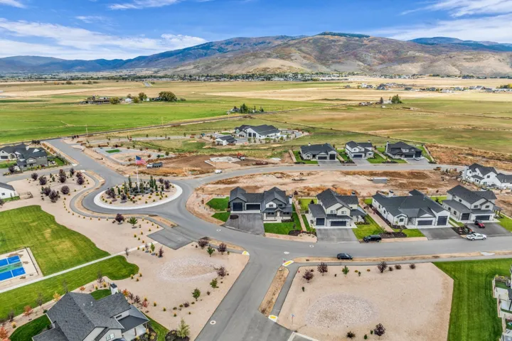 Residential development featuring modern homes, a tennis court, a central roundabout, and natural landscape