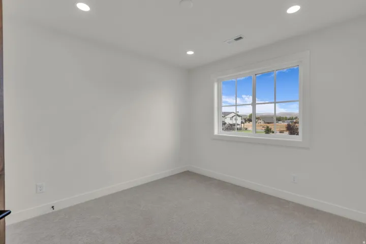 Recessed lighting, light-toned carpeting, white walls, and a multi-pane window with white trim