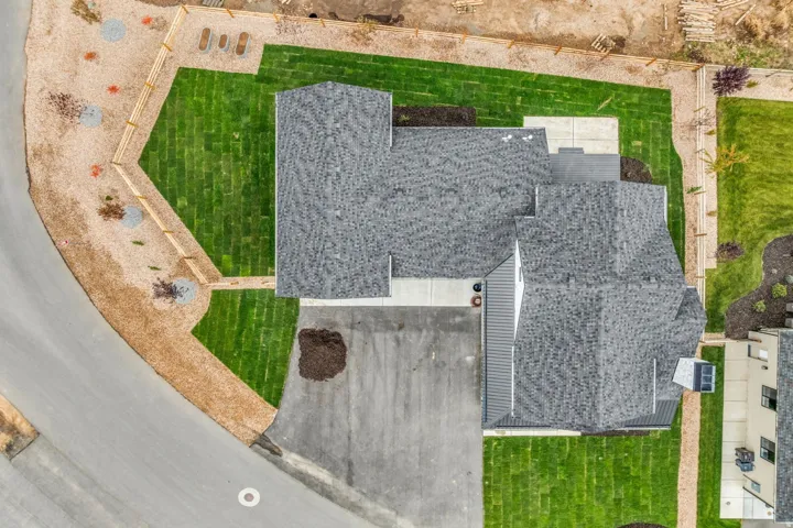 Asphalt shingle roof, paved driveway, concrete walkways, and established green lawn