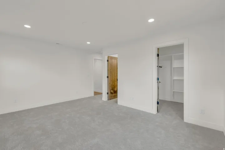 Recessed lighting, light gray carpet, white walls, and a built-in closet with shelving