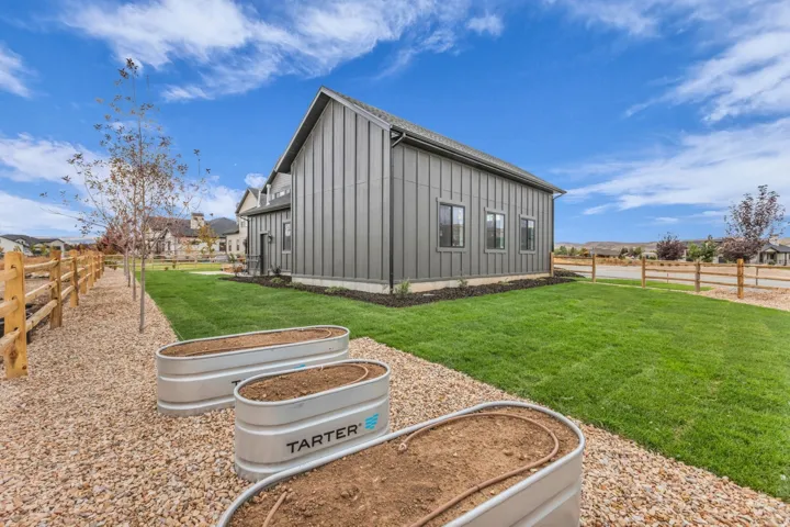 Modern vertical siding exterior with multiple windows, surrounded by a manicured lawn and gravel landscaping
