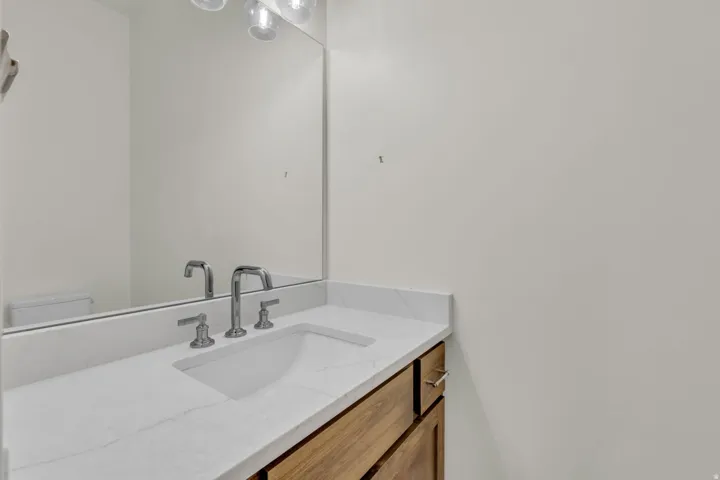 White countertop with integrated sink, chrome faucet, and wood-finish vanity