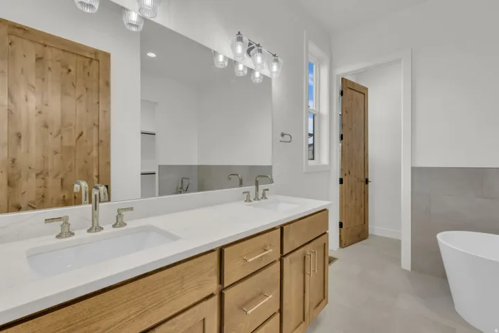 Dual vanity with stone-finish countertop, wood-finish cabinetry, and brushed nickel fixtures