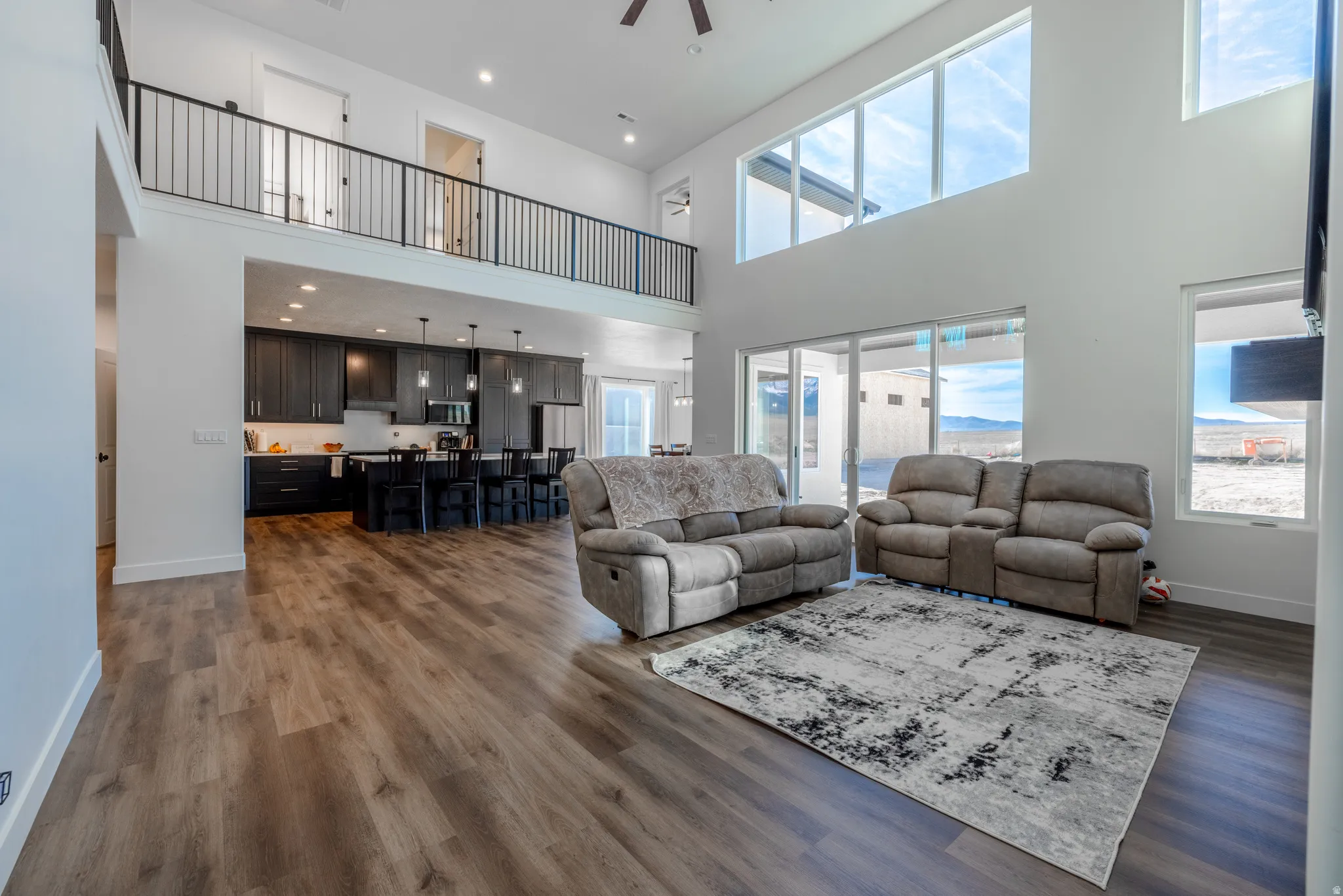 Two-story living area with high ceilings, wood-finish flooring, and large windows