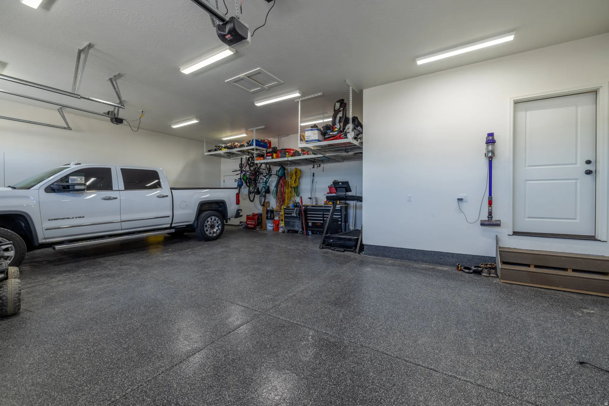 Spacious garage with epoxy flooring, overhead storage, abundant task lighting, and direct access door