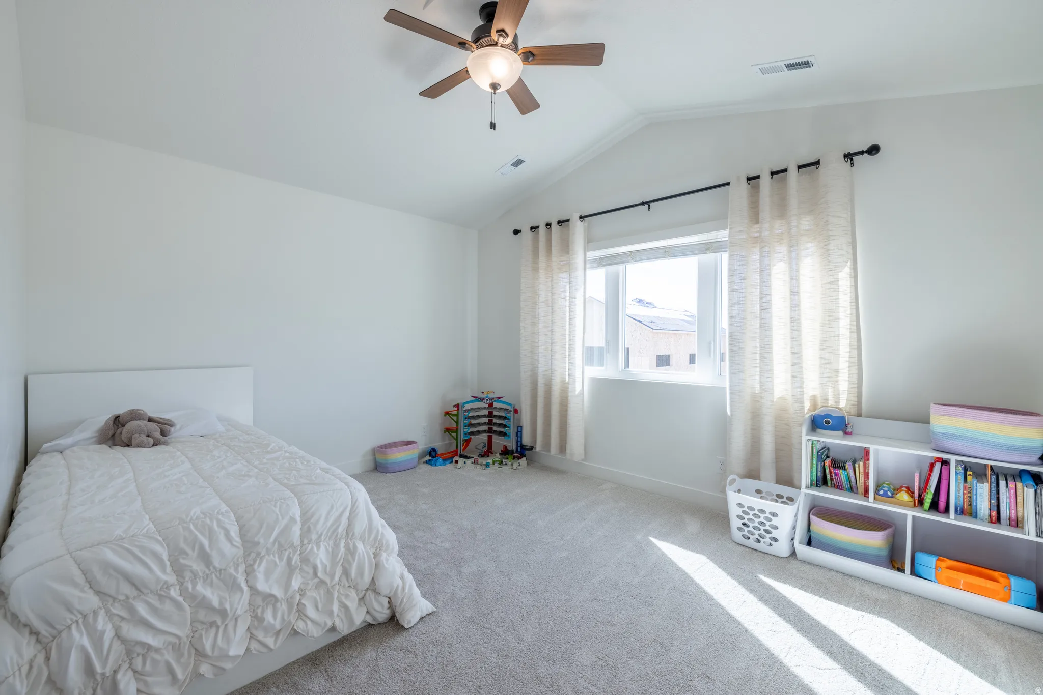 Bedroom 4 ~ Vaulted ceiling with a ceiling fan, light-colored carpeting, white walls, and a window with a black curtain rod
