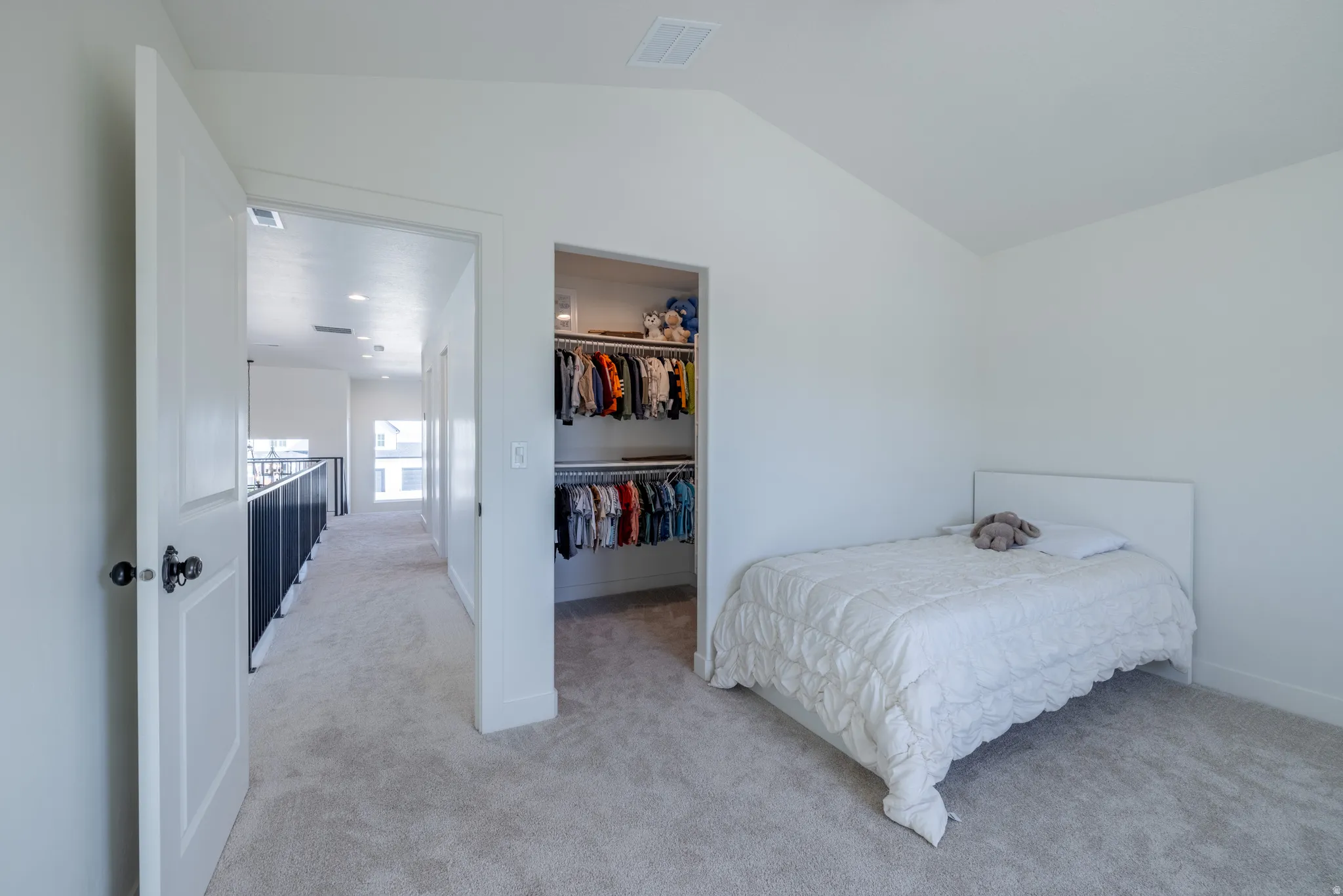 Bedroom 4~ Carpeted room featuring a vaulted ceiling and an open closet with built-in shelving and hanging rods