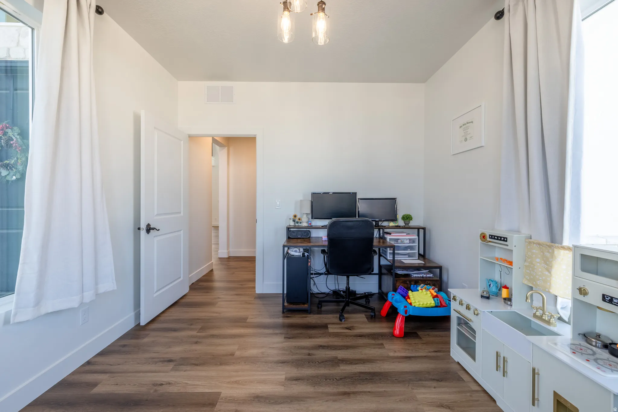 Wood-finish flooring, white walls, white trim, recessed lighting, and a modern light fixture