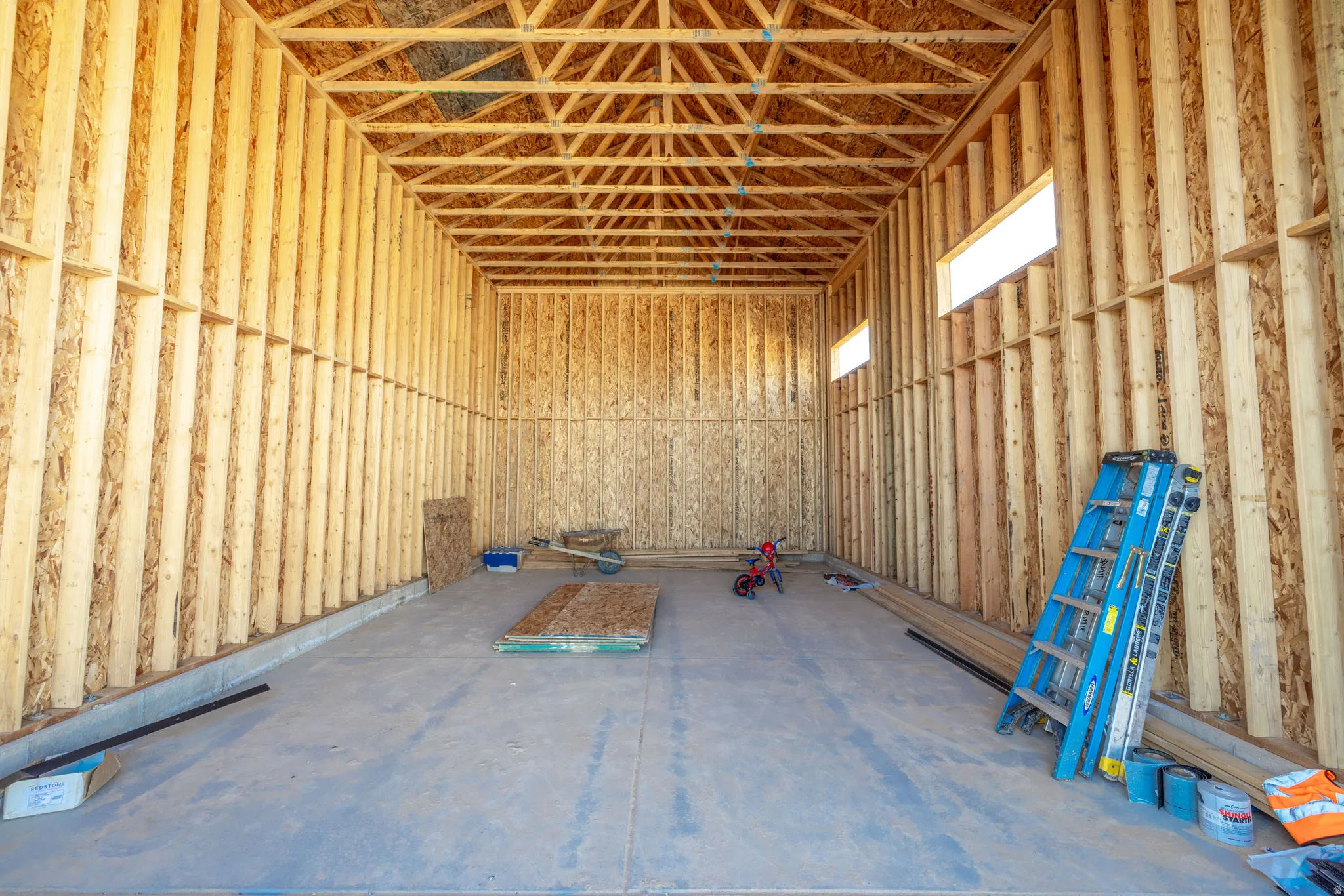 Exposed wood framing with visible ceiling trusses and subfloor