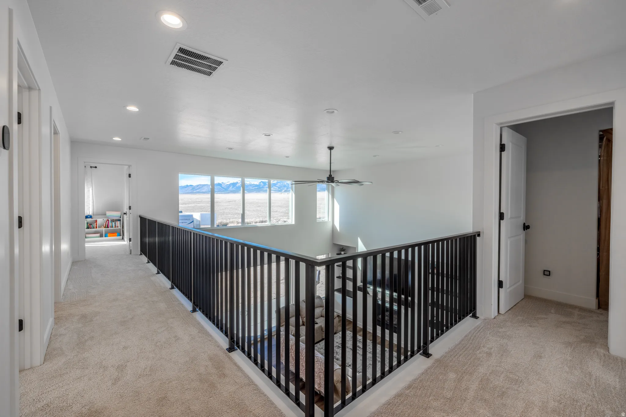Loft space with black metal railing, recessed lighting, and a ceiling fan