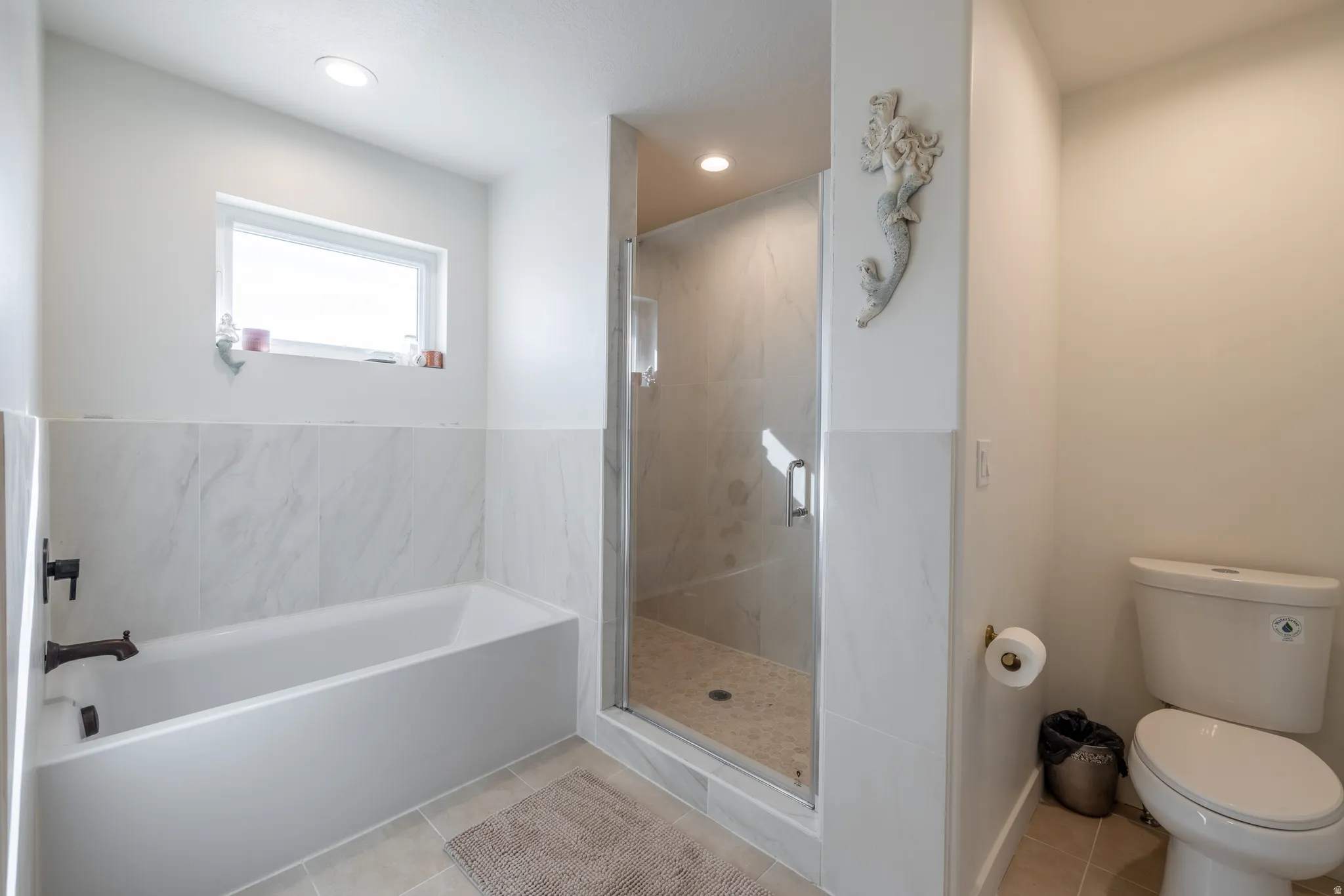 Bathtub with dark-toned fixtures, tile surround, and a rectangular window