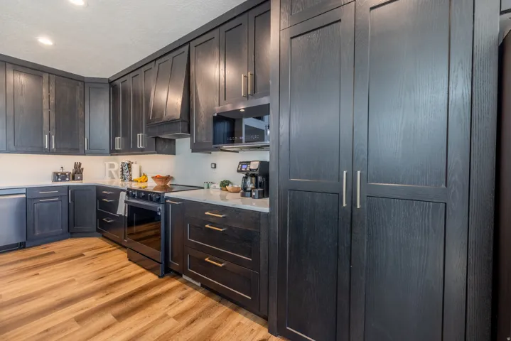 Kitchen featuring dark-stained cabinetry, wood-finish flooring, recessed lighting, and a built-in oven with a cooktop
