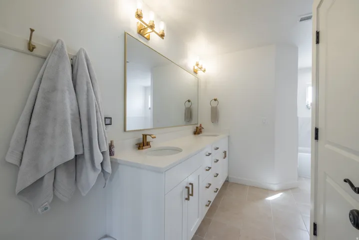 Dual vanity with integrated sinks, white cabinetry, and brushed gold hardware