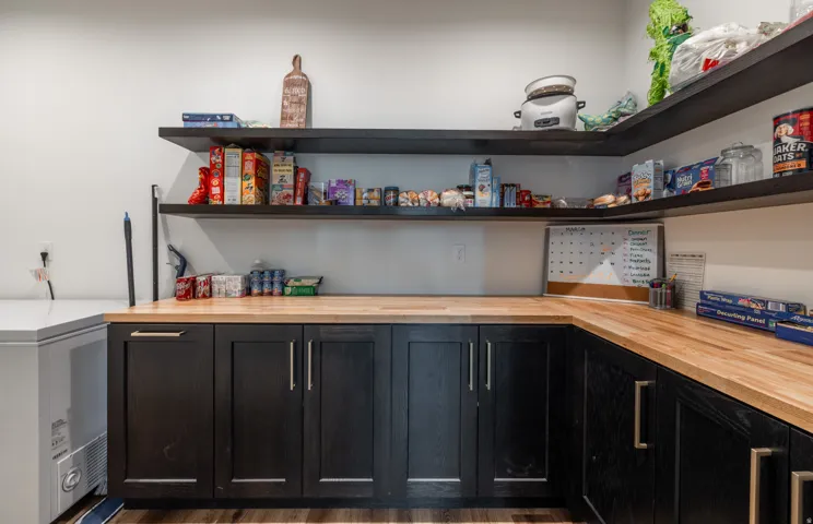 Built-in black cabinetry with metal hardware, light wood-finish countertops, and open shelving