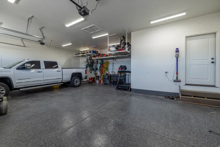 Spacious garage with epoxy flooring, overhead storage, abundant task lighting, and direct access door