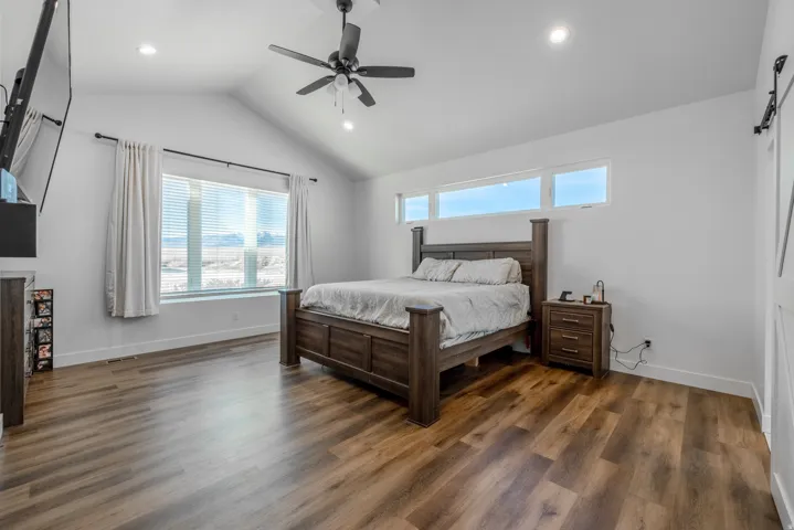 Primary Bedroom, . Vaulted ceiling with a ceiling fan, recessed lighting, wood-finish flooring, and large windows Electic fireplace