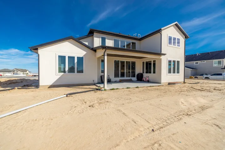 Stucco exterior with black trim, multiple large windows, covered patio, and concrete patio