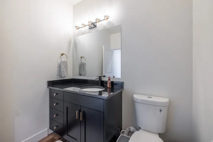 1/2 bath Black vanity with an integrated sink, dark countertop, and gold-finish hardware