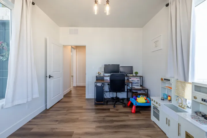 Wood-finish flooring, white walls, white trim, recessed lighting, and a modern light fixture