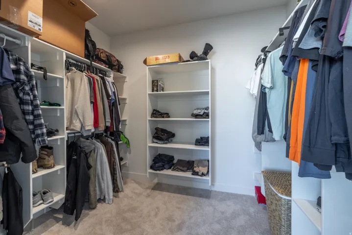 Integrated custom shelving system with multiple hanging rods, built-in open shelving, and plush carpet flooring