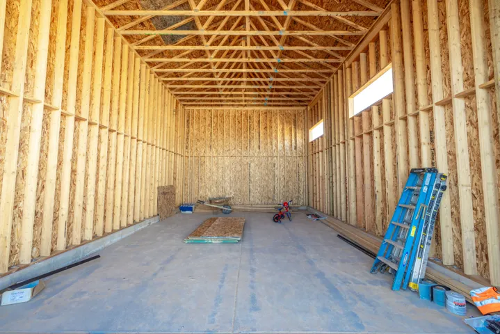 Exposed wood framing with visible ceiling trusses and subfloor