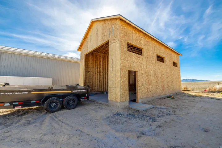Unfinished outbuilding featuring a concrete slab foundation, wood framing, and multiple window openings