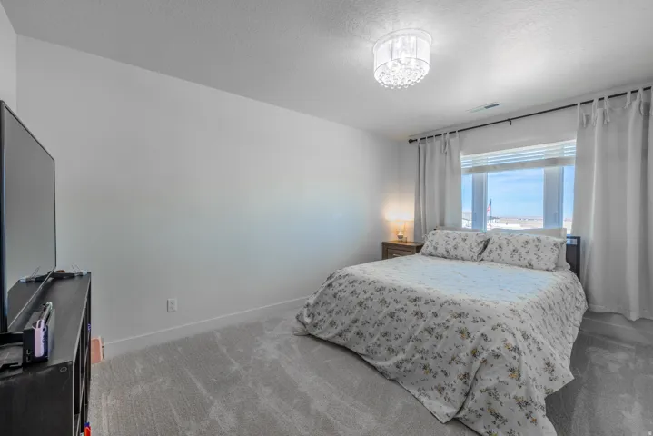 Bedroom 2~ Recessed window featuring horizontal blinds and drapes, accompanied by a bedside table with a lamp