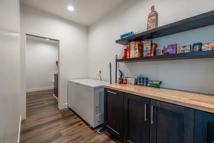 Wood-finish flooring, recessed lighting, and built-in shelving complement the cabinetry and wood countertop
