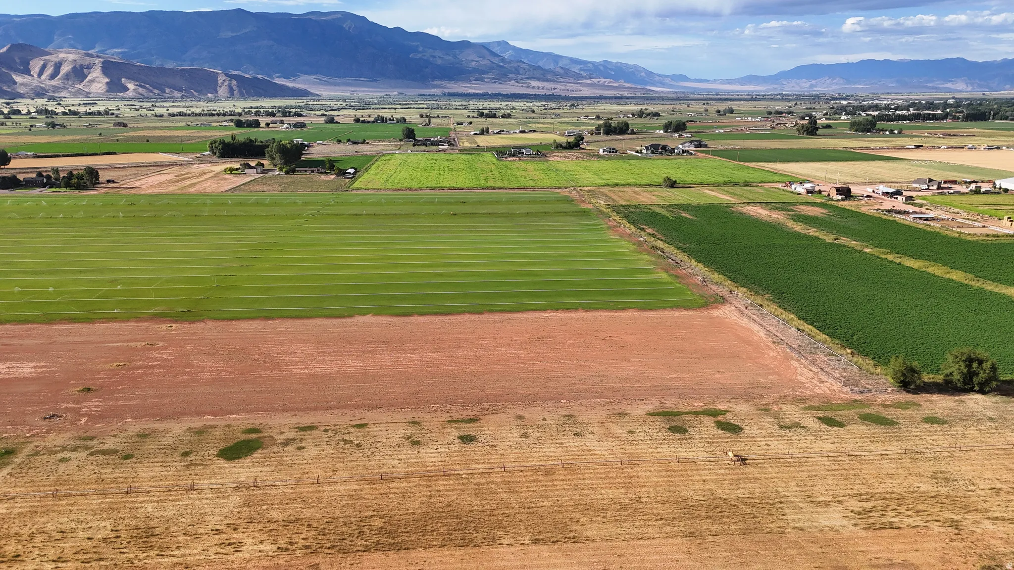 Expansive agricultural land featuring cultivated fields and a distant mountainous backdrop