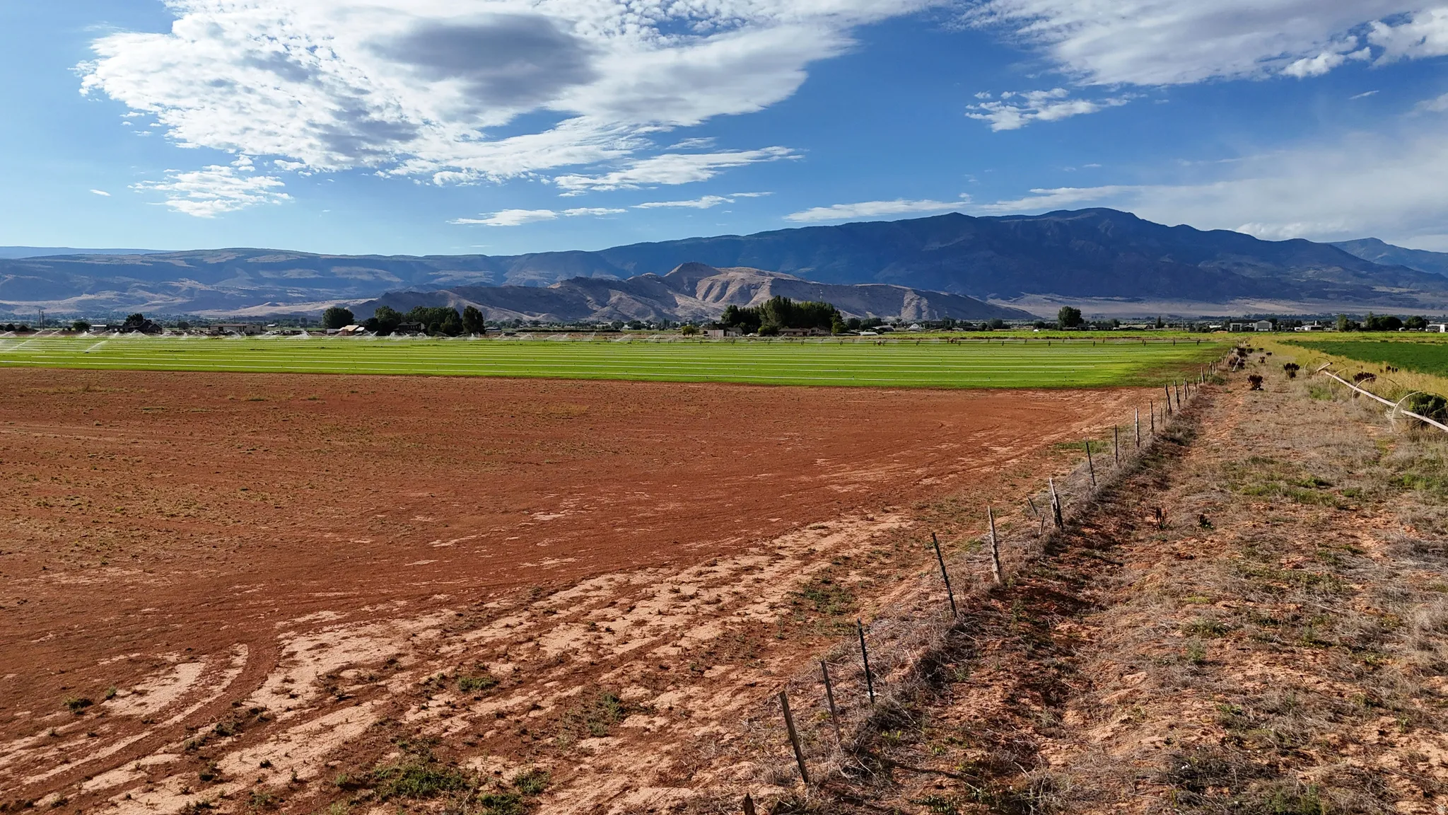 Expansive land parcel featuring open fields, distant mountains, and a perimeter fence